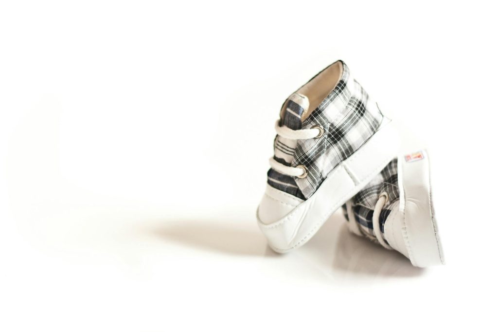 Pair of stylish checkered baby shoes with reflection and clean white background.