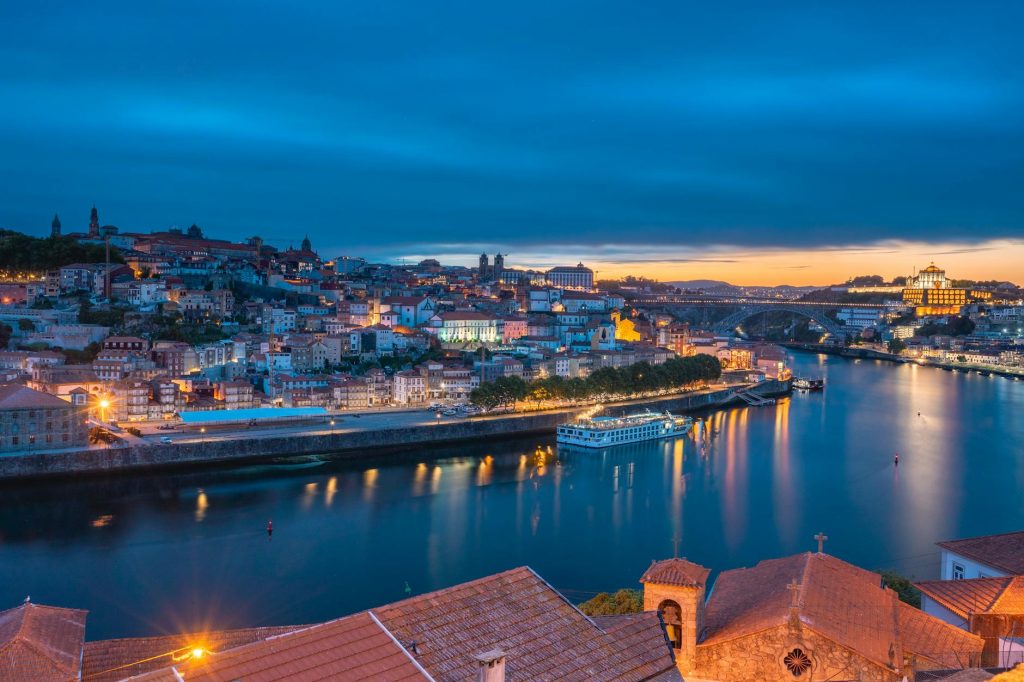 Scenic view of Porto, Portugal at dusk showcasing the Douro River and city lights.