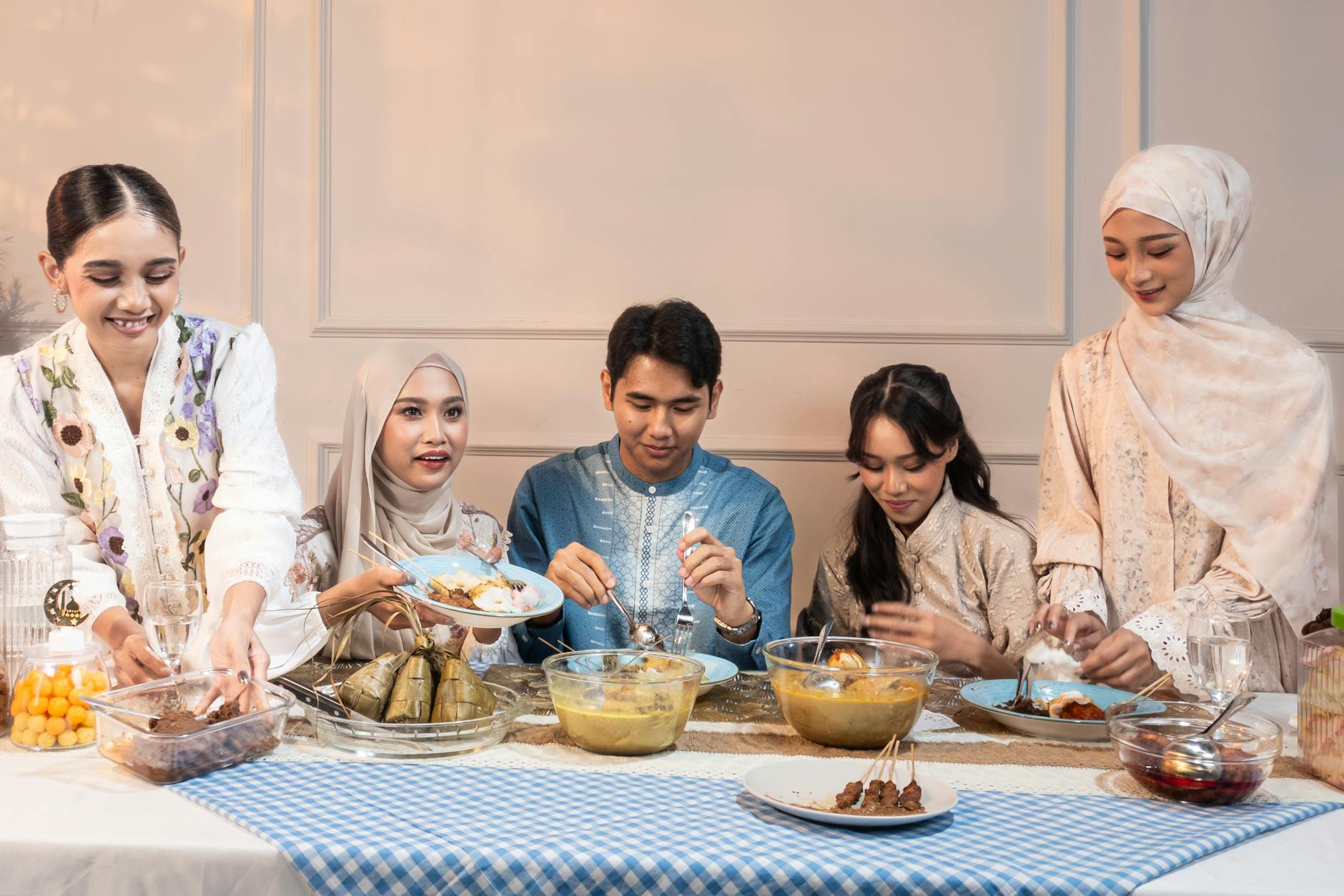 A joyful Indonesian family shares a traditional meal during Eid, featuring festive clothing and delicious dishes.