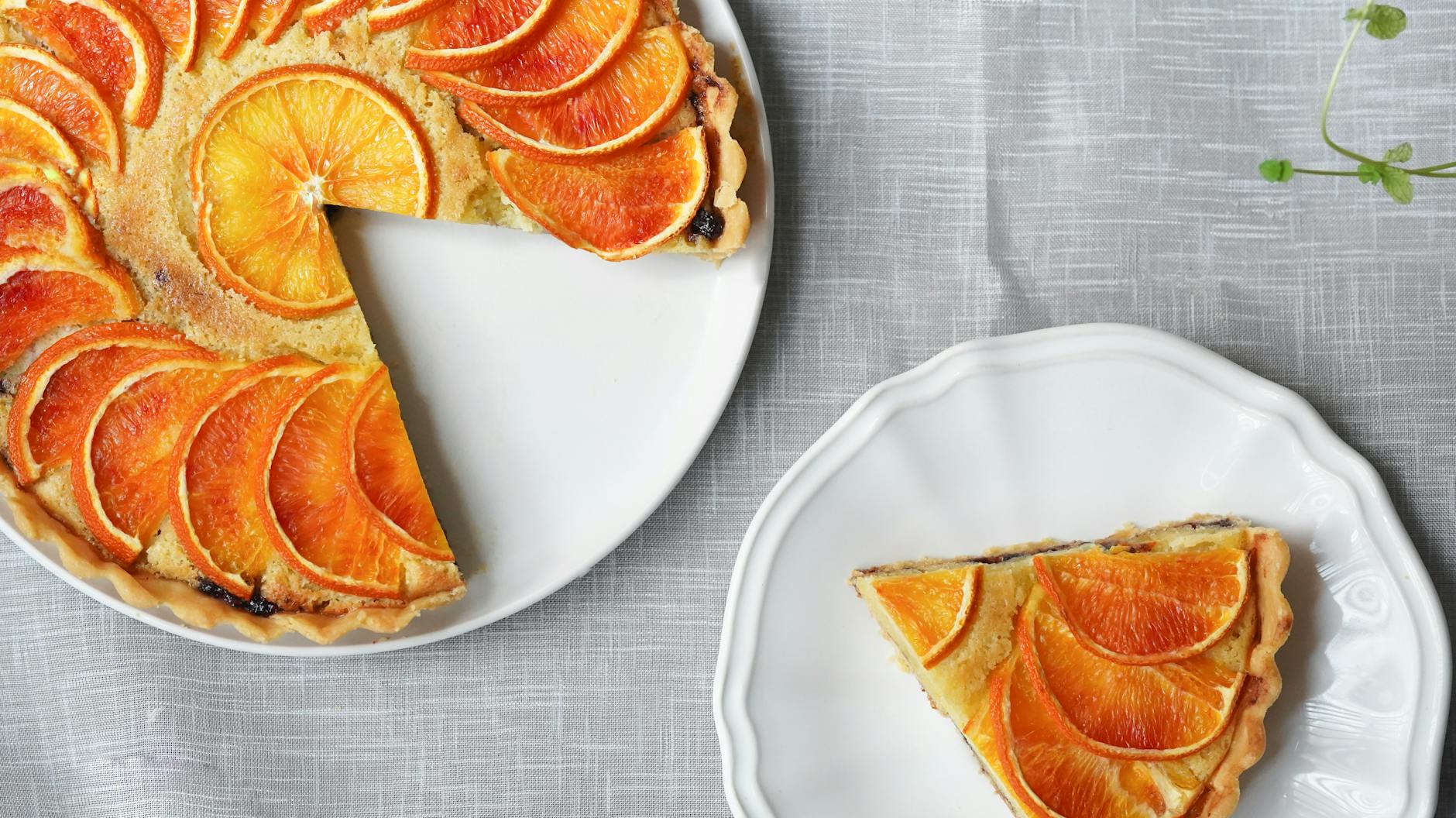 Freshly baked orange citrus tart with a slice served on a white plate.