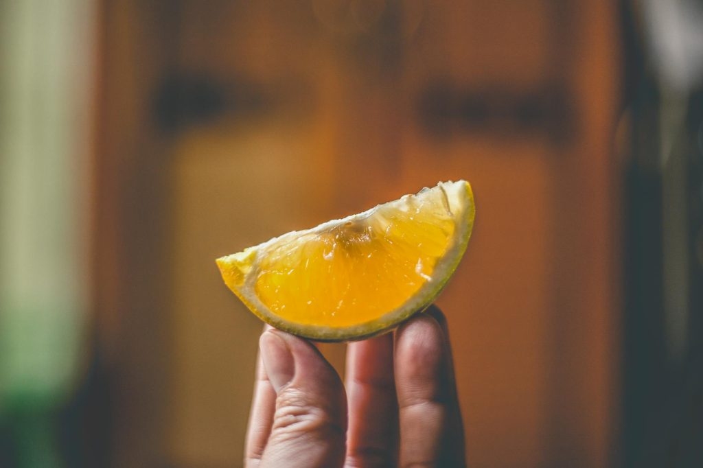 A close-up shot of a fresh lemon slice held by a hand, capturing the essence of freshness.