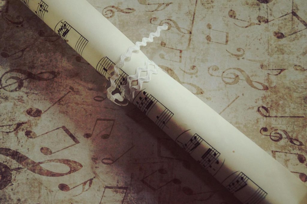 Artistic photo of a rolled sheet music on a textured surface, featuring musical notes.