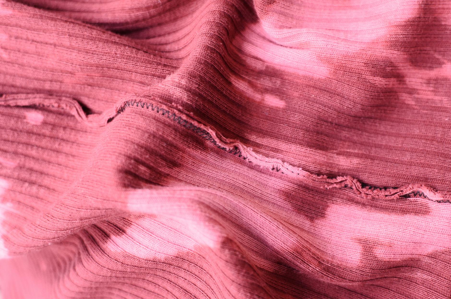 From above abstract background of pink knitted textile with inside seam on table