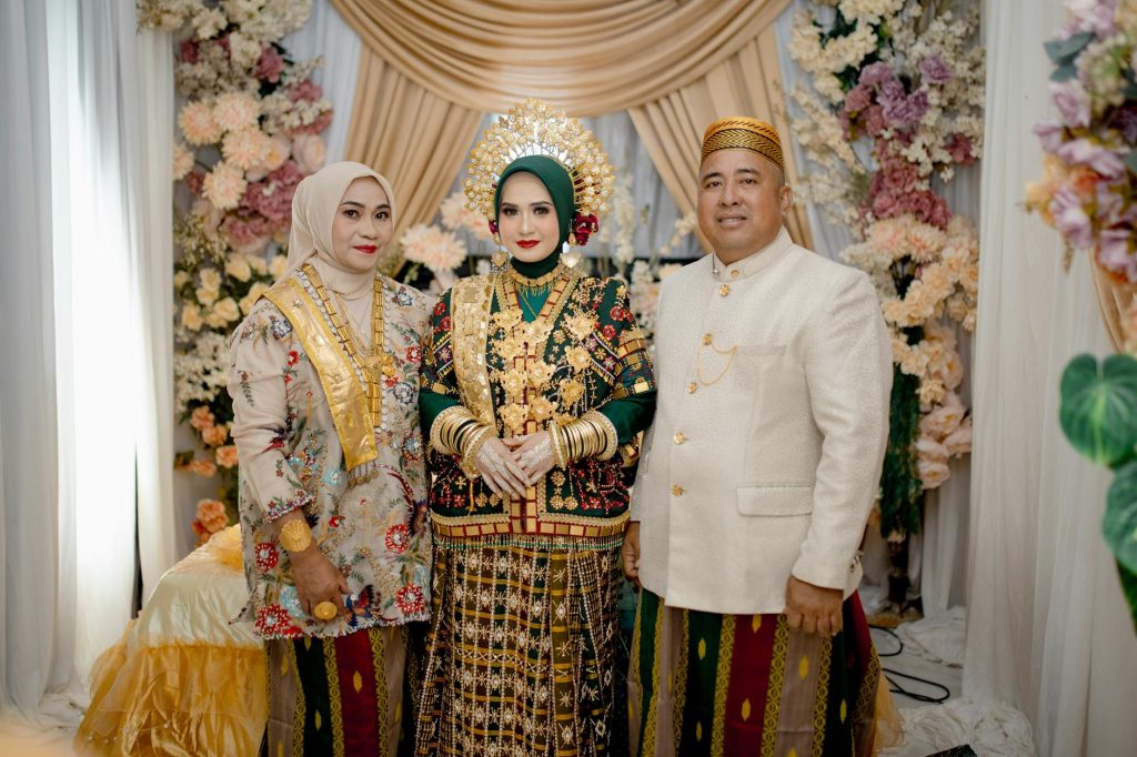Bride in Bugis traditional attire with family in Kendari, Indonesia.
